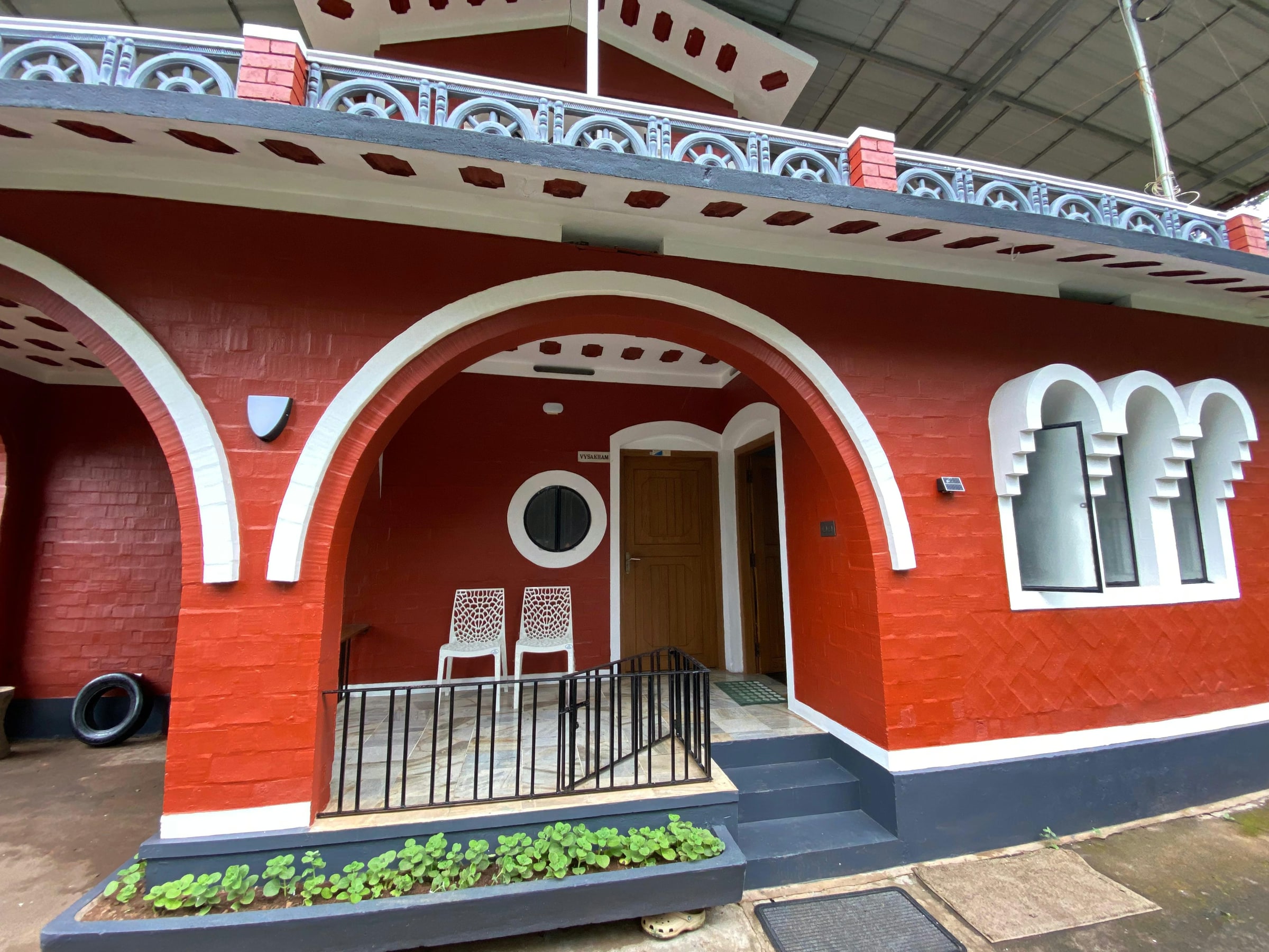 Red porch entrance with white arches and chairs